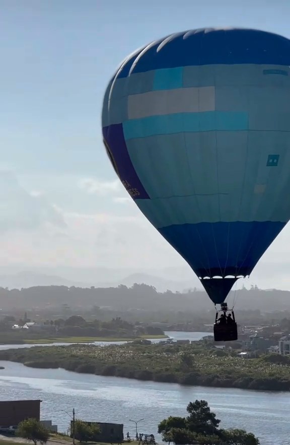 Balão sobrevoando um vale com rio ao amanhecer